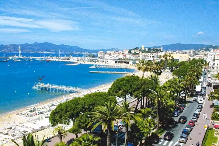 Aerial view of Cannes beach promenade with palm trees, marina, and blue Mediterranean Sea on French Riviera