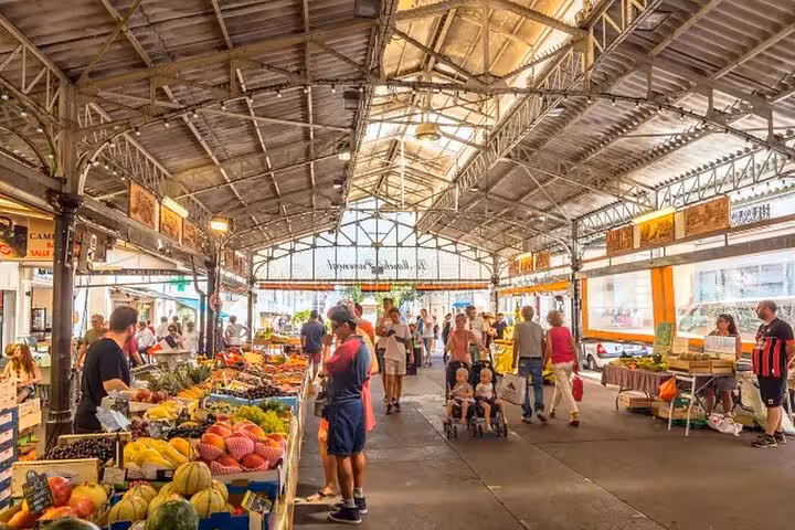Busy covered market hall with colorful fresh fruit and vegetable stalls in Cannes, French Riviera