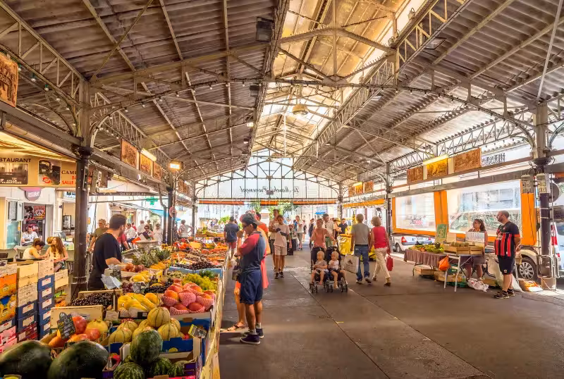 Bustling covered market hall with fresh fruit and vegetable stalls and shoppers in Cannes, France