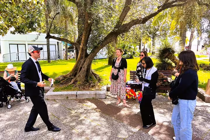 Tour guide leading a small group of visitors on a walking tour in a sunny Cannes park