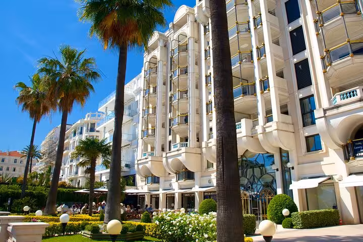Elegant grand hotel facade with palm trees and manicured gardens on Cannes French Riviera day tour