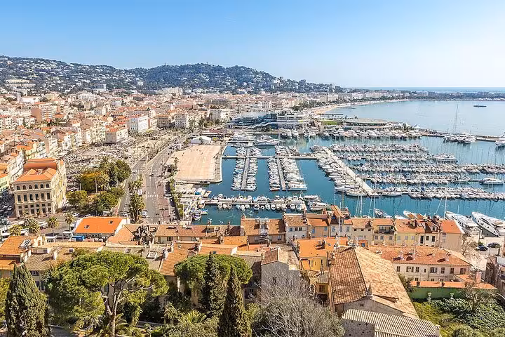 Aerial view of Cannes harbor with yachts, marina, and colorful buildings along the French Riviera coastline