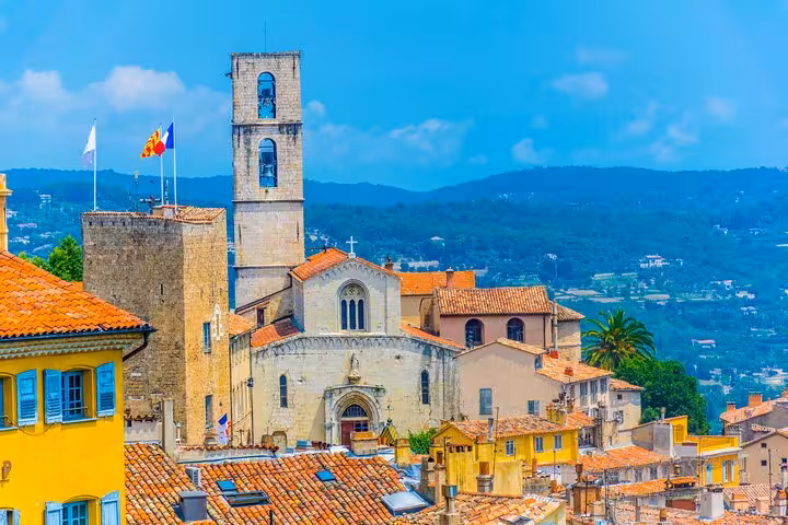 Aerial view of Cannes old town with cathedral bell tower, terracotta rooftops, and green hills