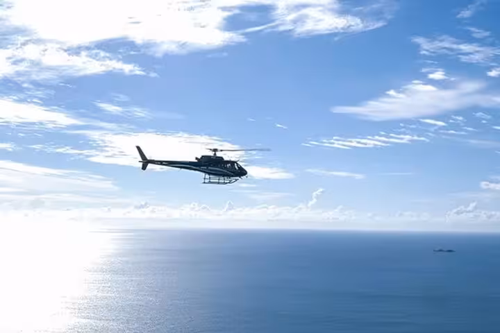 Helicopter flying over the Mediterranean Sea with blue skies and scattered clouds near Cannes