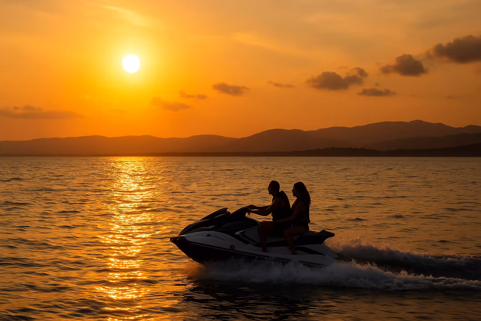Couple riding a jet ski at golden sunset near Cannes Lerins Islands no license required tour