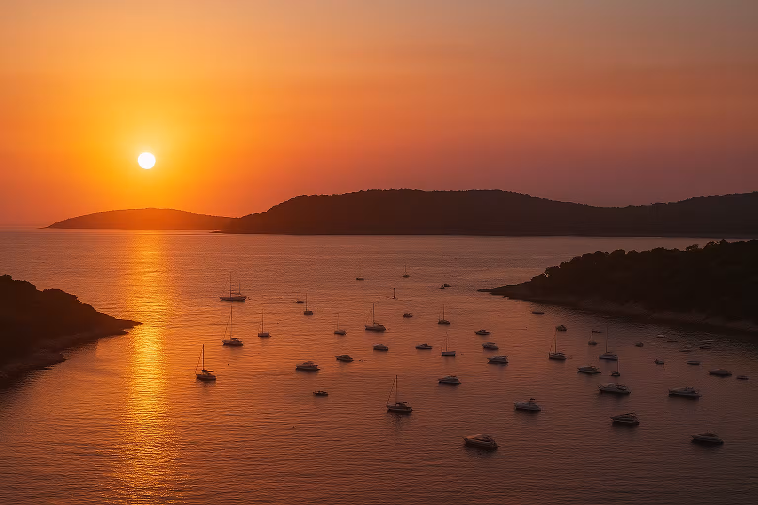 Golden sunset over Lerins Islands with sailboats anchored in calm bay near Cannes