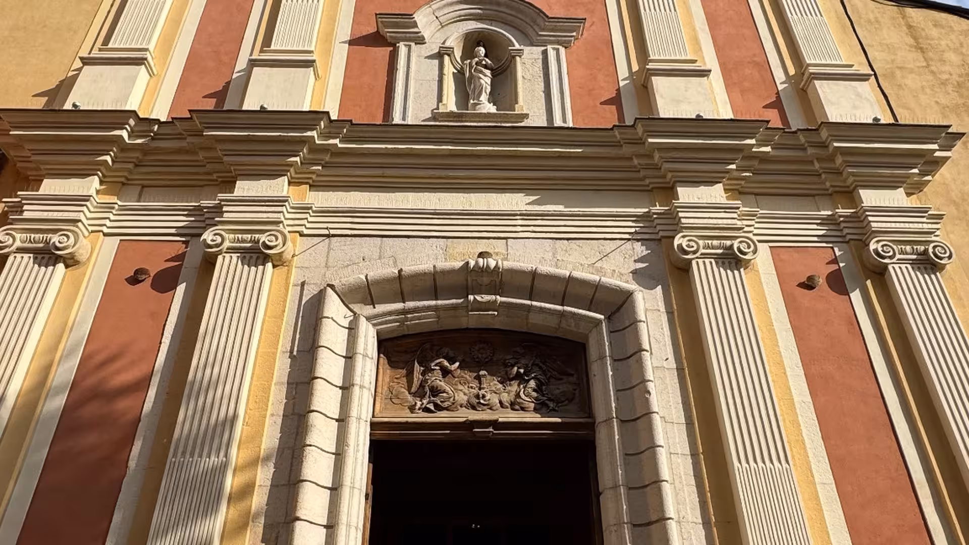 Baroque church facade with ionic columns and statue niche in Cannes, France