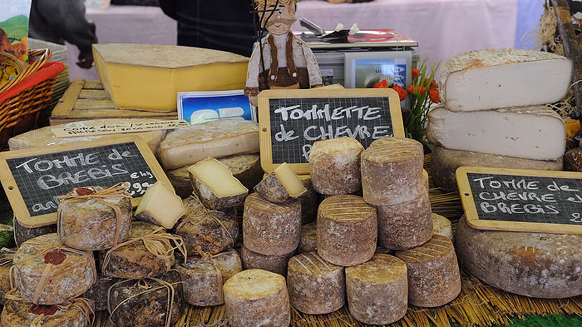 French cheese market stall in Cannes displaying Tomme de Brebis and Tommette de Chèvre varieties