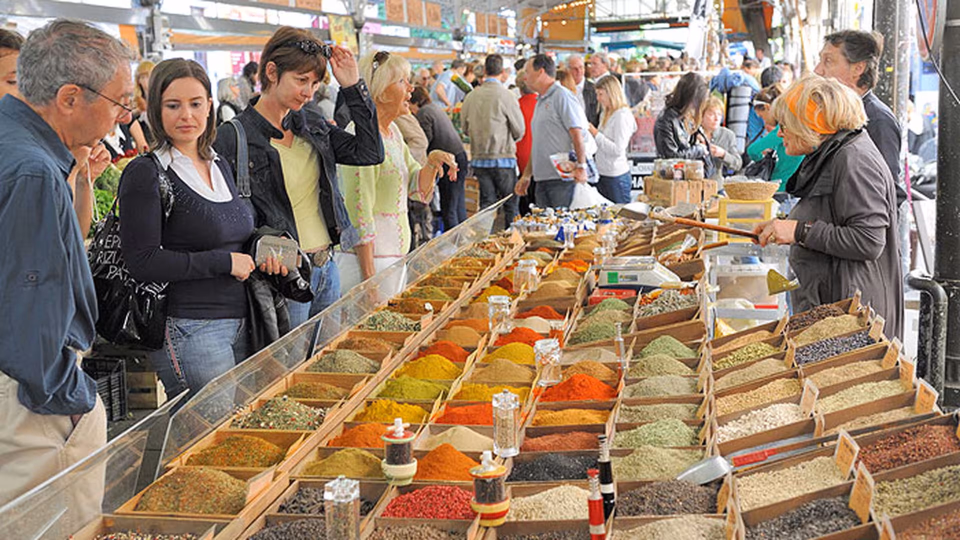 Colorful spice market stall with locals browsing vibrant mounds of spices in Cannes, France
