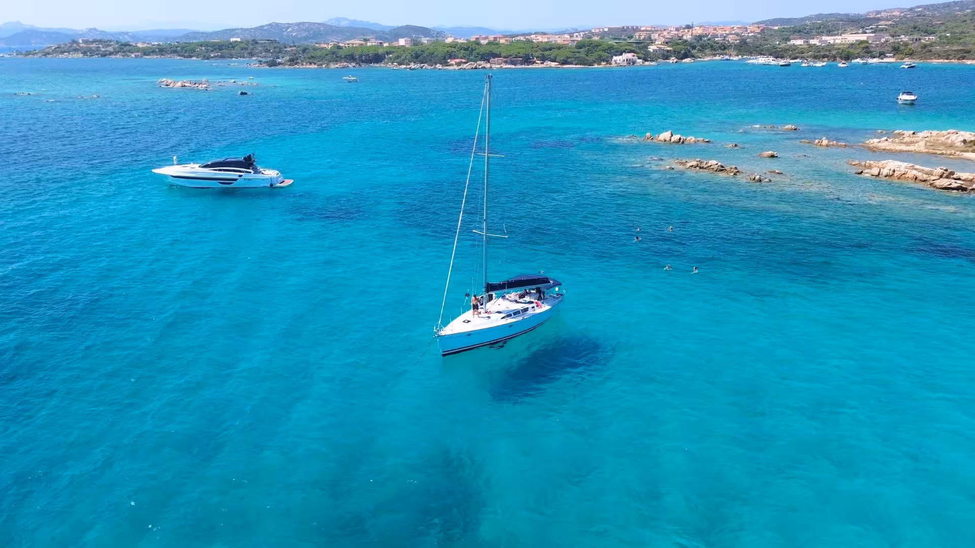 Sailboat anchored in the clear blue waters of La Maddalena Archipelago, ideal for a Cannigione full day tour.
