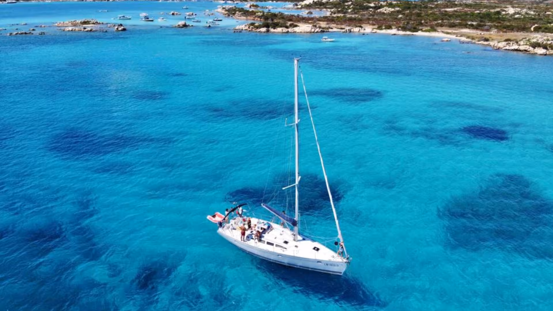 Sailboat gliding on crystal-clear waters of La Maddalena Archipelago during a full-day tour from Cannigione.
