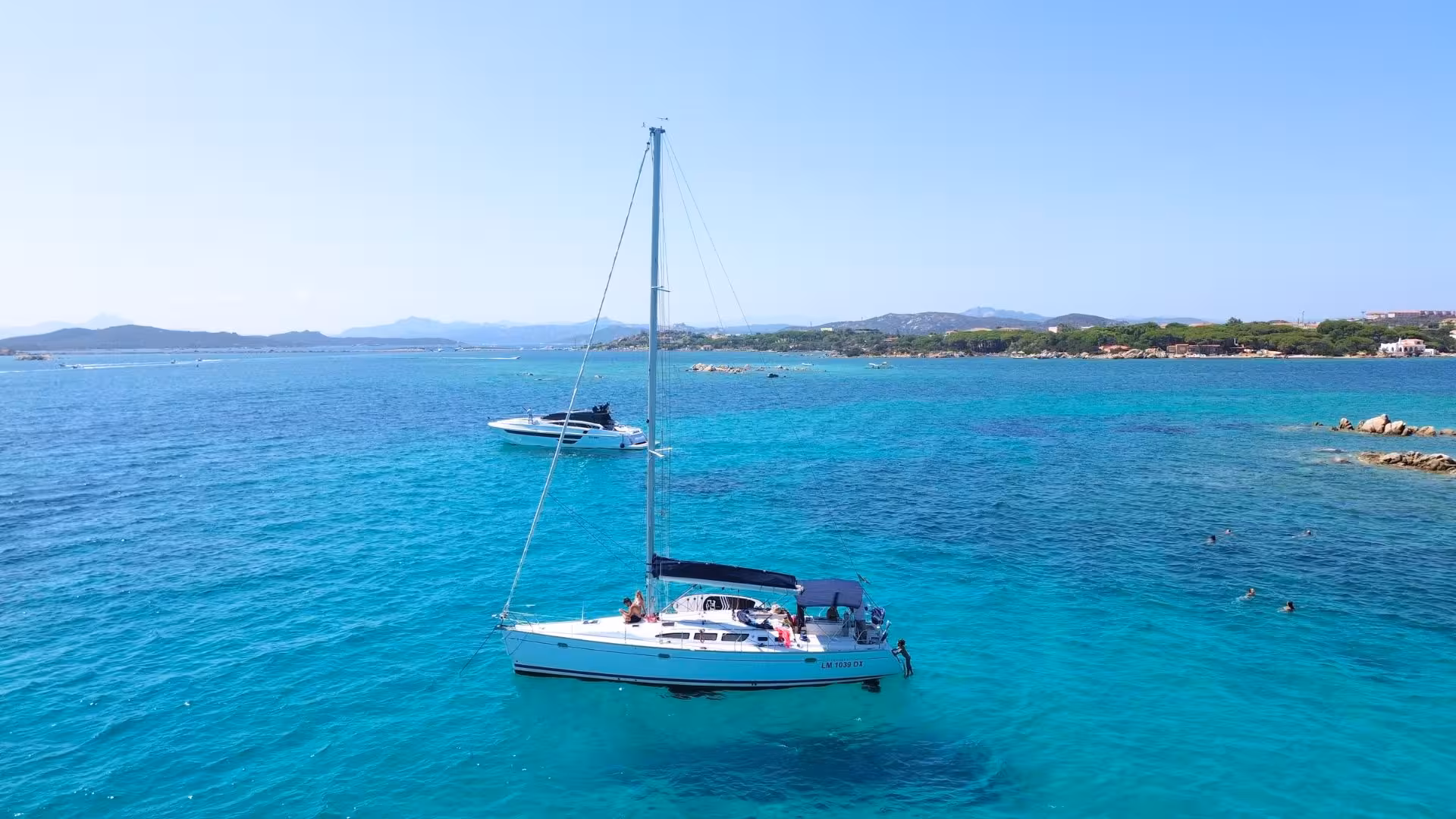 Scenic view of a sailboat anchored in La Maddalena Archipelago's turquoise waters, perfect for a Cannigione day tour.