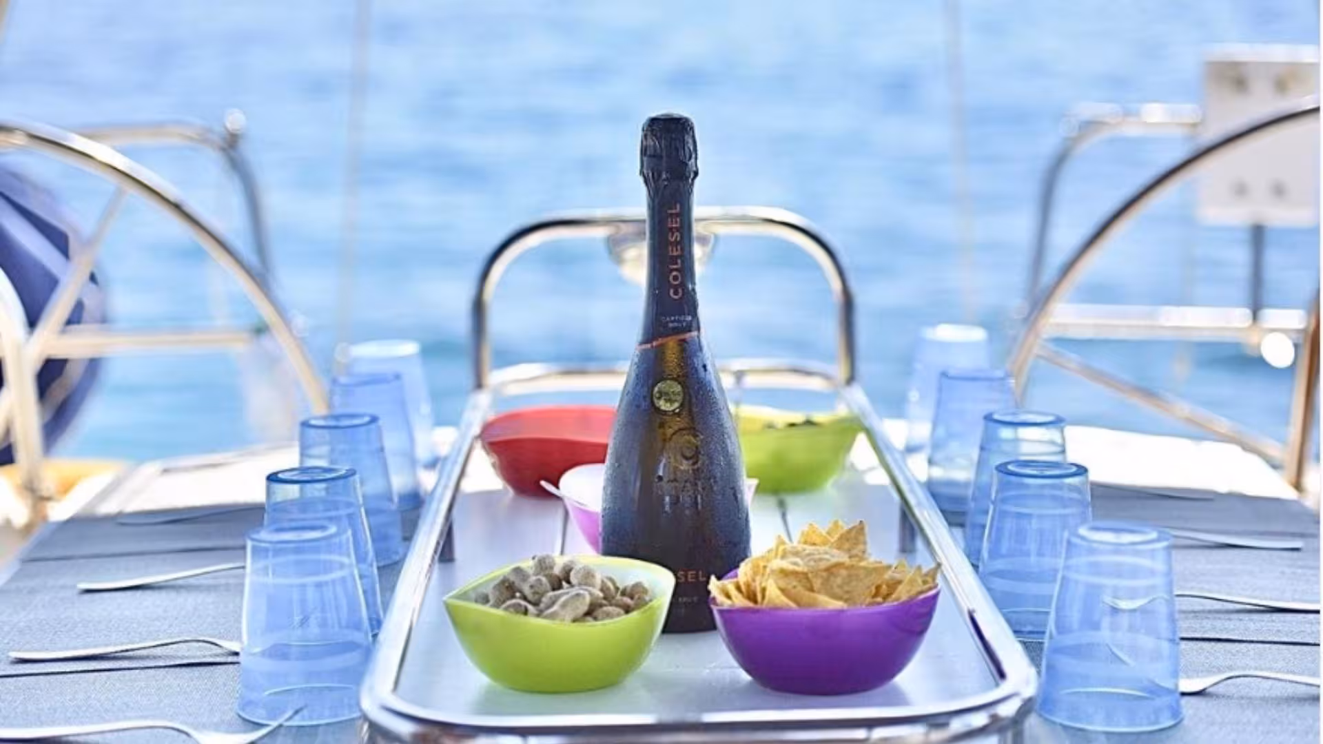 Elegantly set sailboat table with wine, snacks, and ocean backdrop on La Maddalena Archipelago sailing tour.