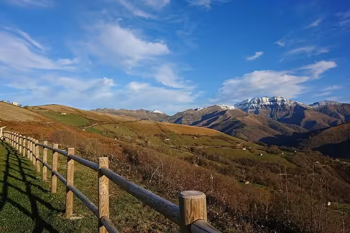Panoramic view of Cantabria's rolling hills and distant mountains under a bright blue sky during a gastronomy tour.