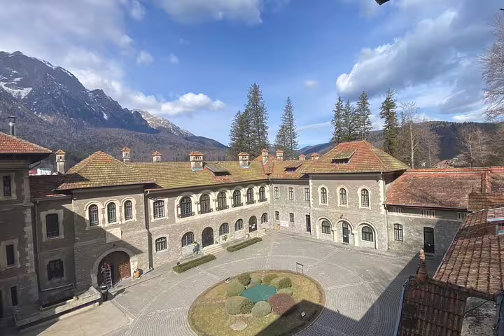 Cantacuzino Castle courtyard with arched stone facade and snow-capped Carpathian mountains in background