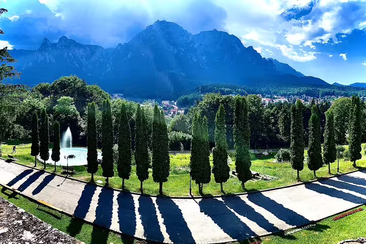 Formal garden with cypress trees and fountain, Cantacuzino Castle grounds with Bucegi Mountains backdrop