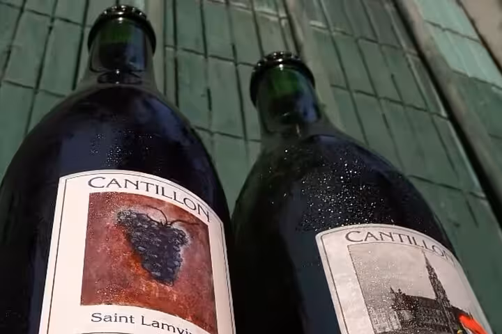 Two Cantillon brewery bottles including Saint Lamvic lambic beer on wooden surface