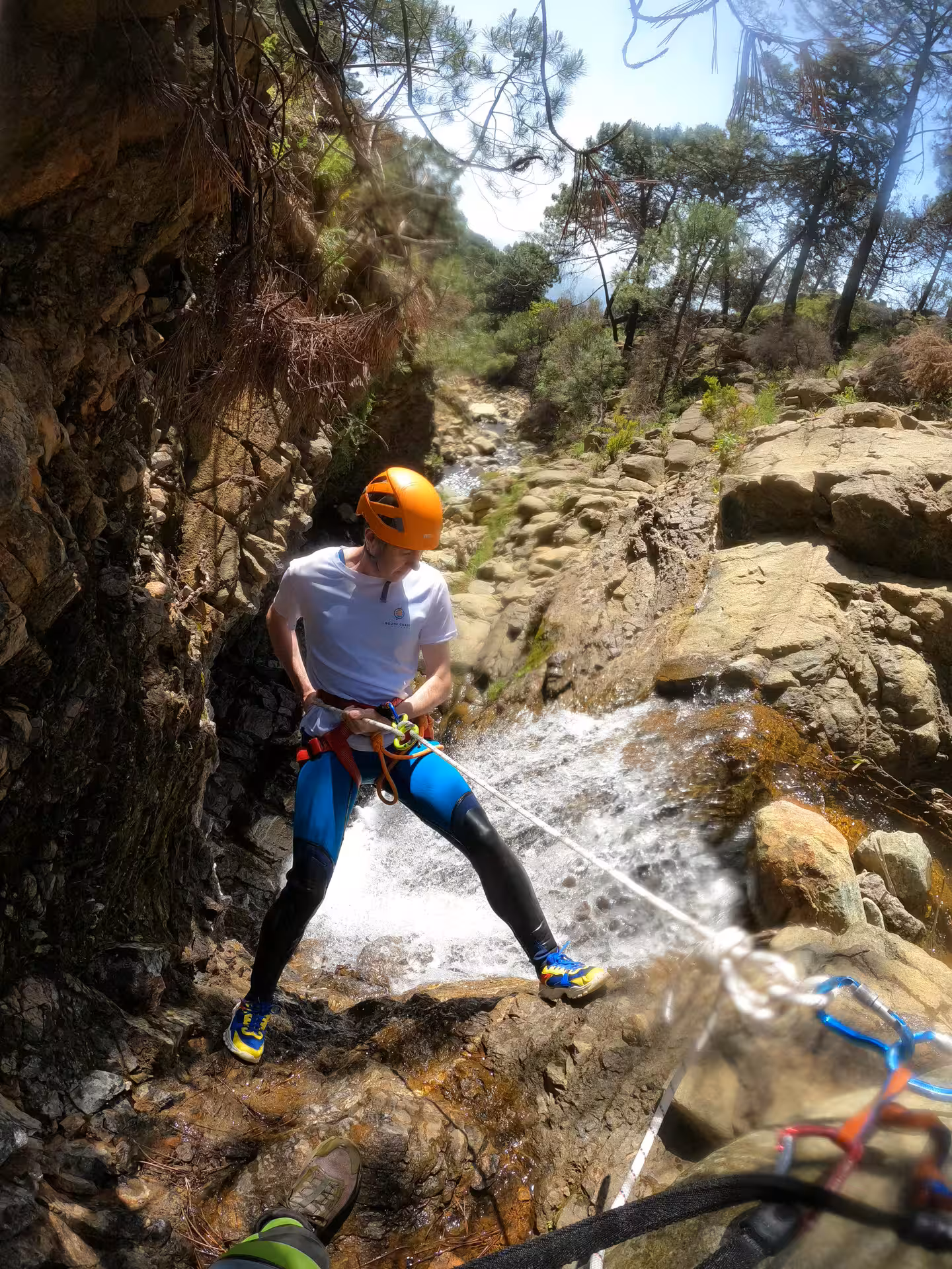 A harnessed canyoneer abseils down a rushing waterfall during a guided canyoning tour in Sierra Bermeja Estepona Spain.