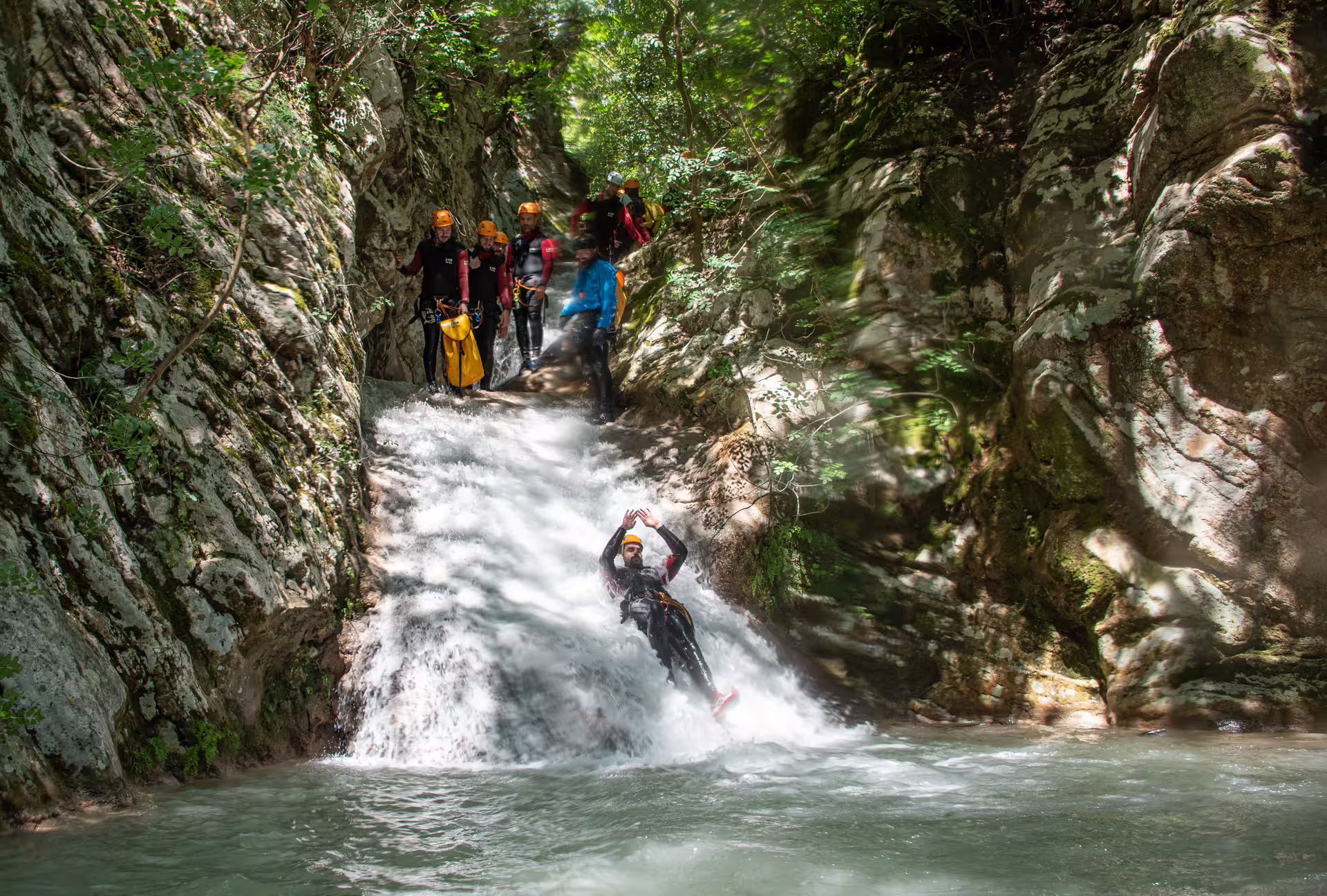 Canyoner slides down a natural waterfall chute into a pool during the Neda Waterfalls canyoning trip in Galicia