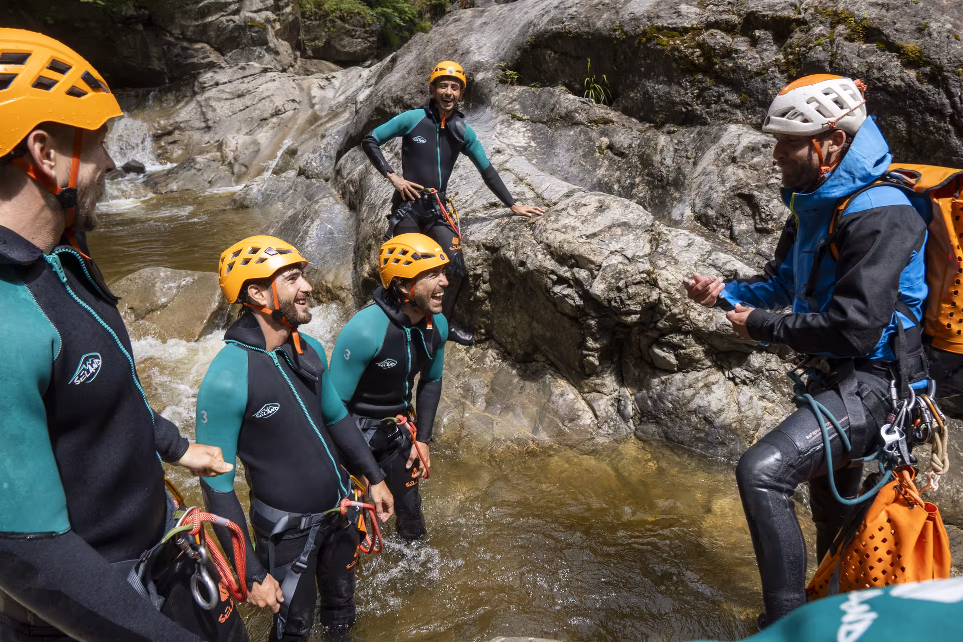 Group of canyoning enthusiasts in wetsuits and helmets enjoying a guided adventure in Chli Schliere near Luzern.