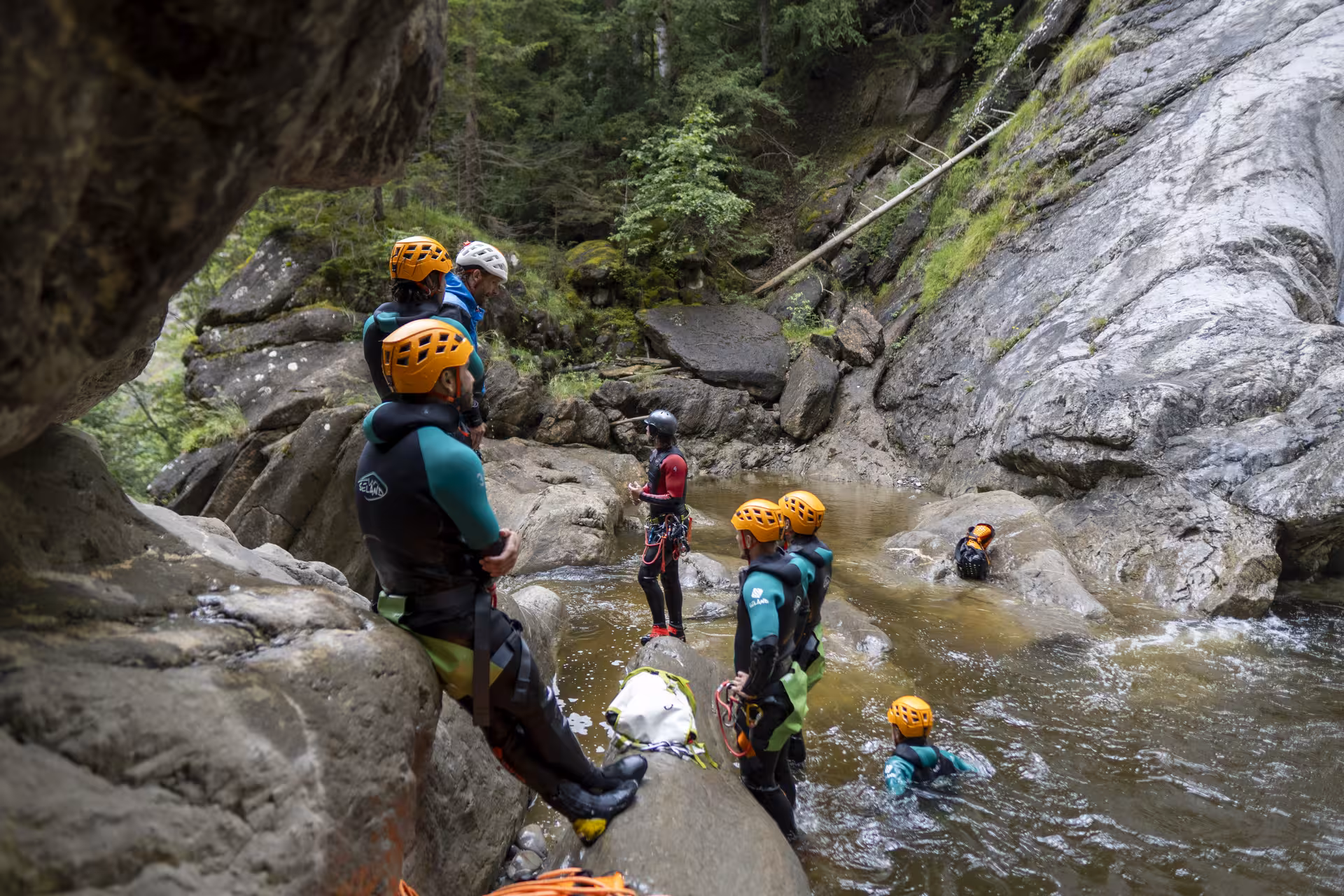 Group of canyoners listening to guide in Chli Schliere, experiencing thrilling canyoning adventure near Luzern.