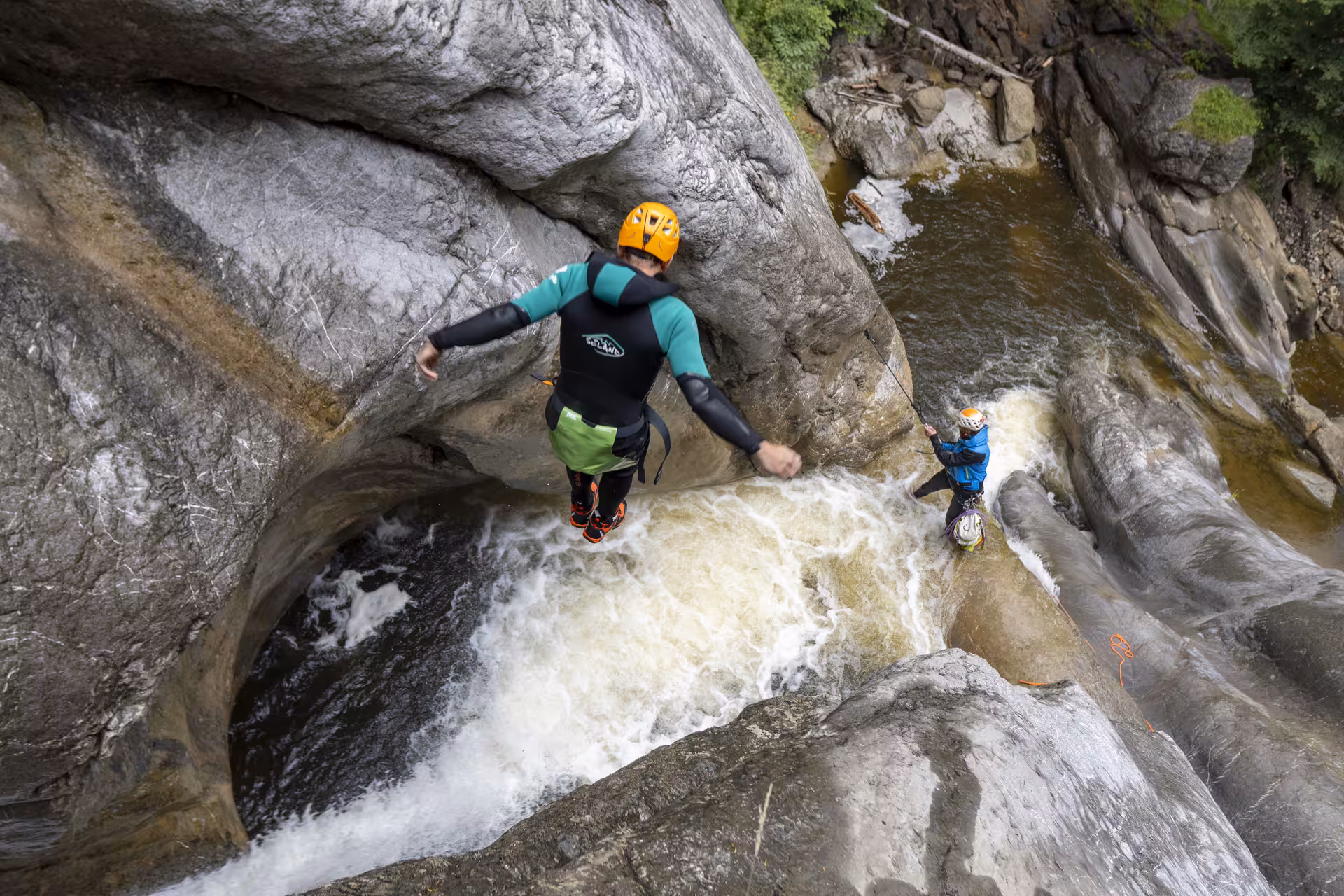 Adventurer jumping into Chli Schliere's canyon waters near Luzern, showcasing thrilling canyoning experience.