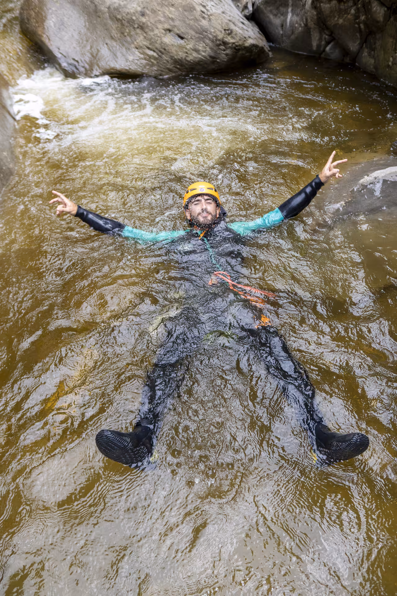 Man in a wetsuit floating and relaxing in a river during a canyoning tour at Chli Schliere, Luzern, enjoying the adventure.
