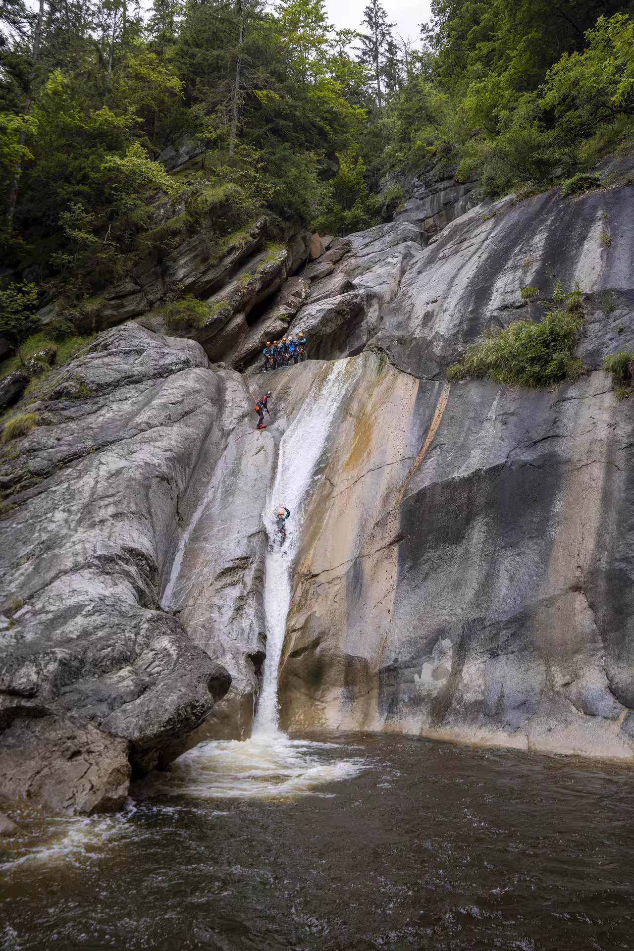 Group of canyoners descending a waterfall at Chli Schliere near Luzern, showcasing thrilling outdoor adventure and natural beauty.