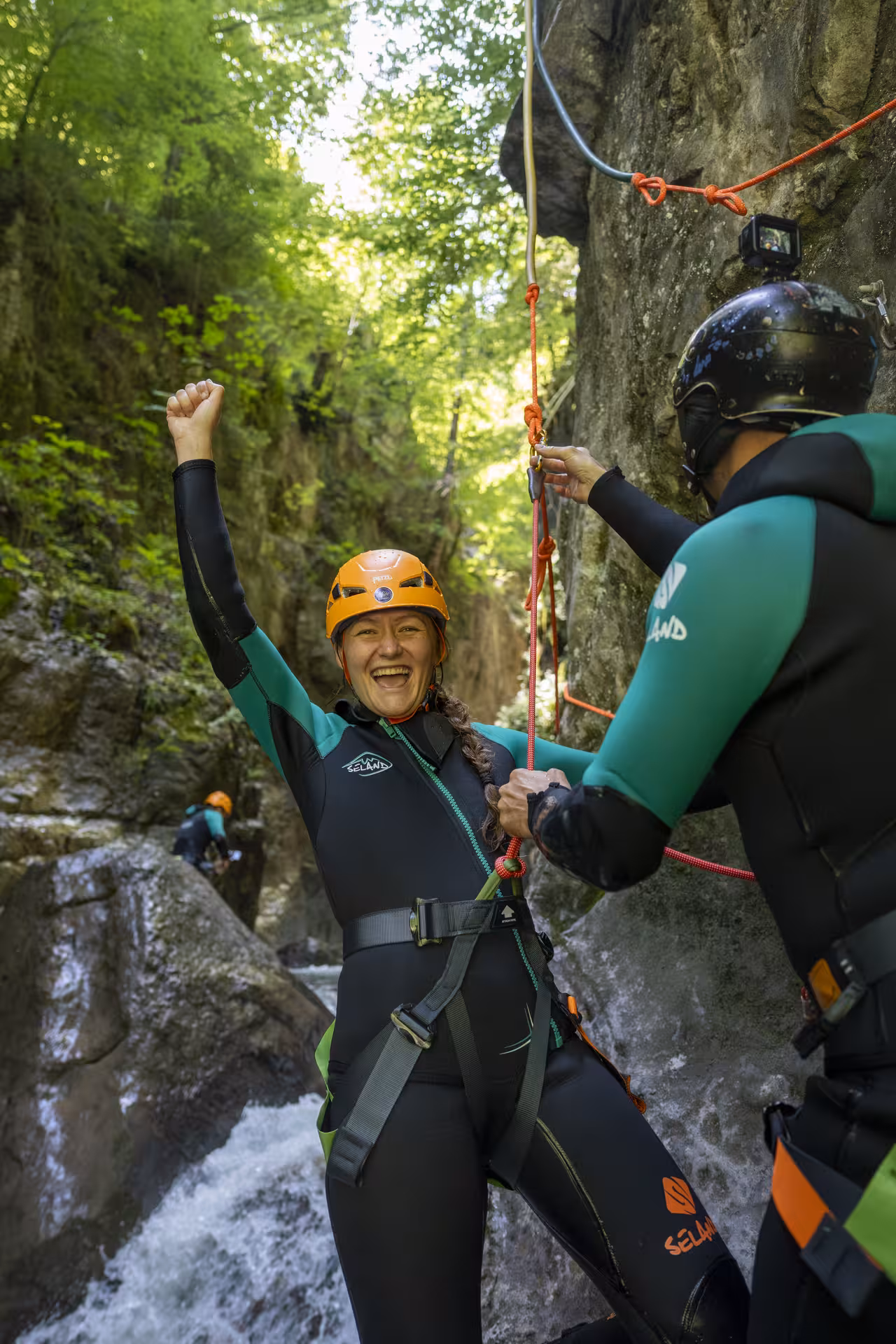 Excited participant celebrates a successful descent during a canyoning tour in the lush Interlaken landscape.
