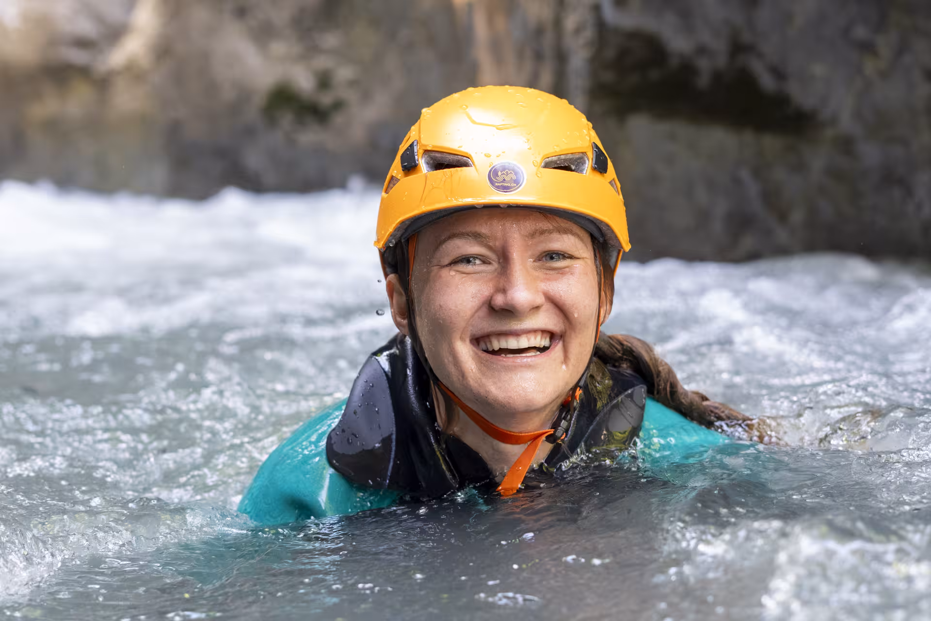 Smiling participant enjoying the refreshing waters of Canyoning Interlaken, wearing a safety helmet and wetsuit.