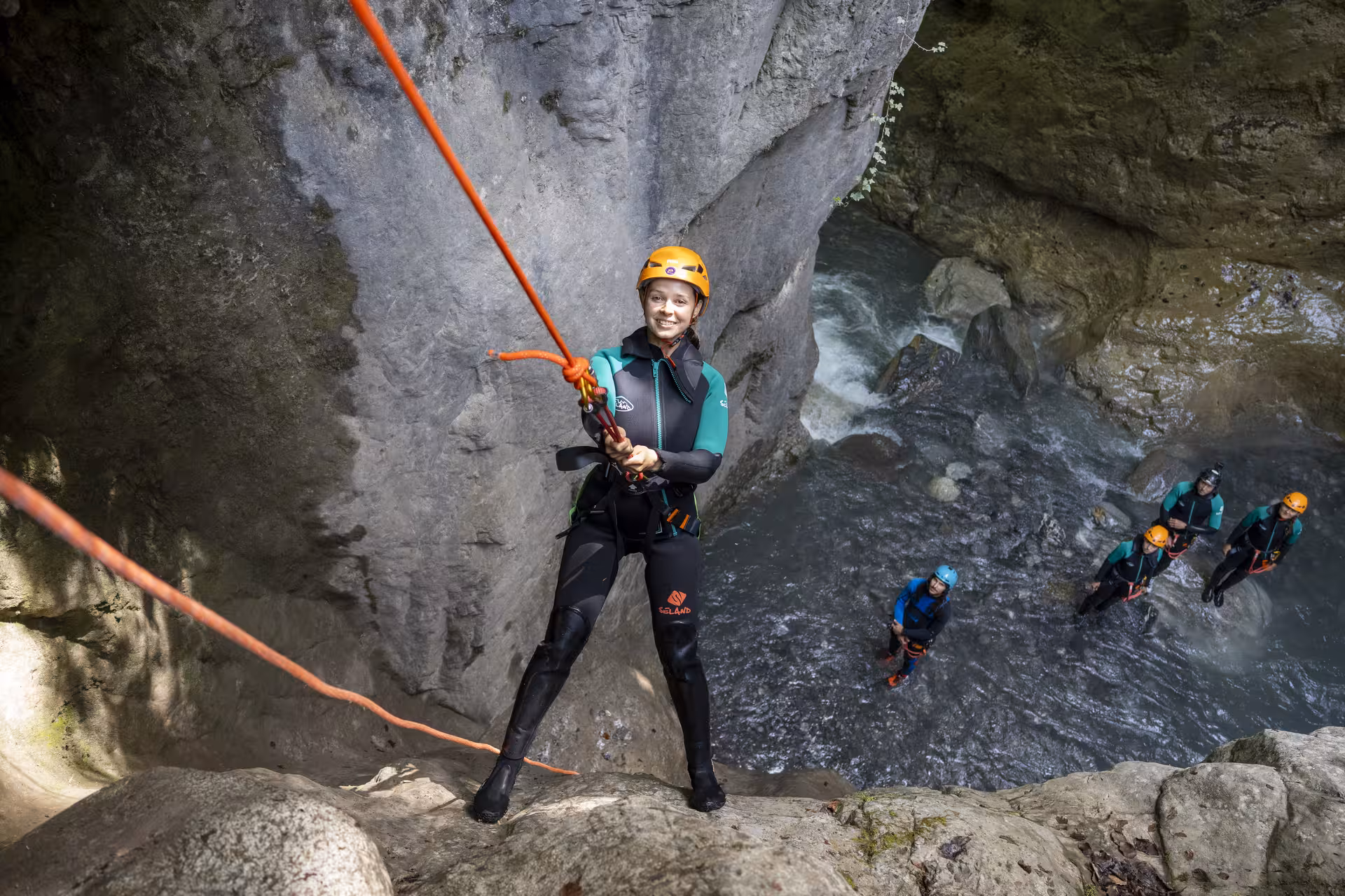 Adventurer in Interlaken rappels with confidence down a canyon wall, surrounded by stunning natural scenery.