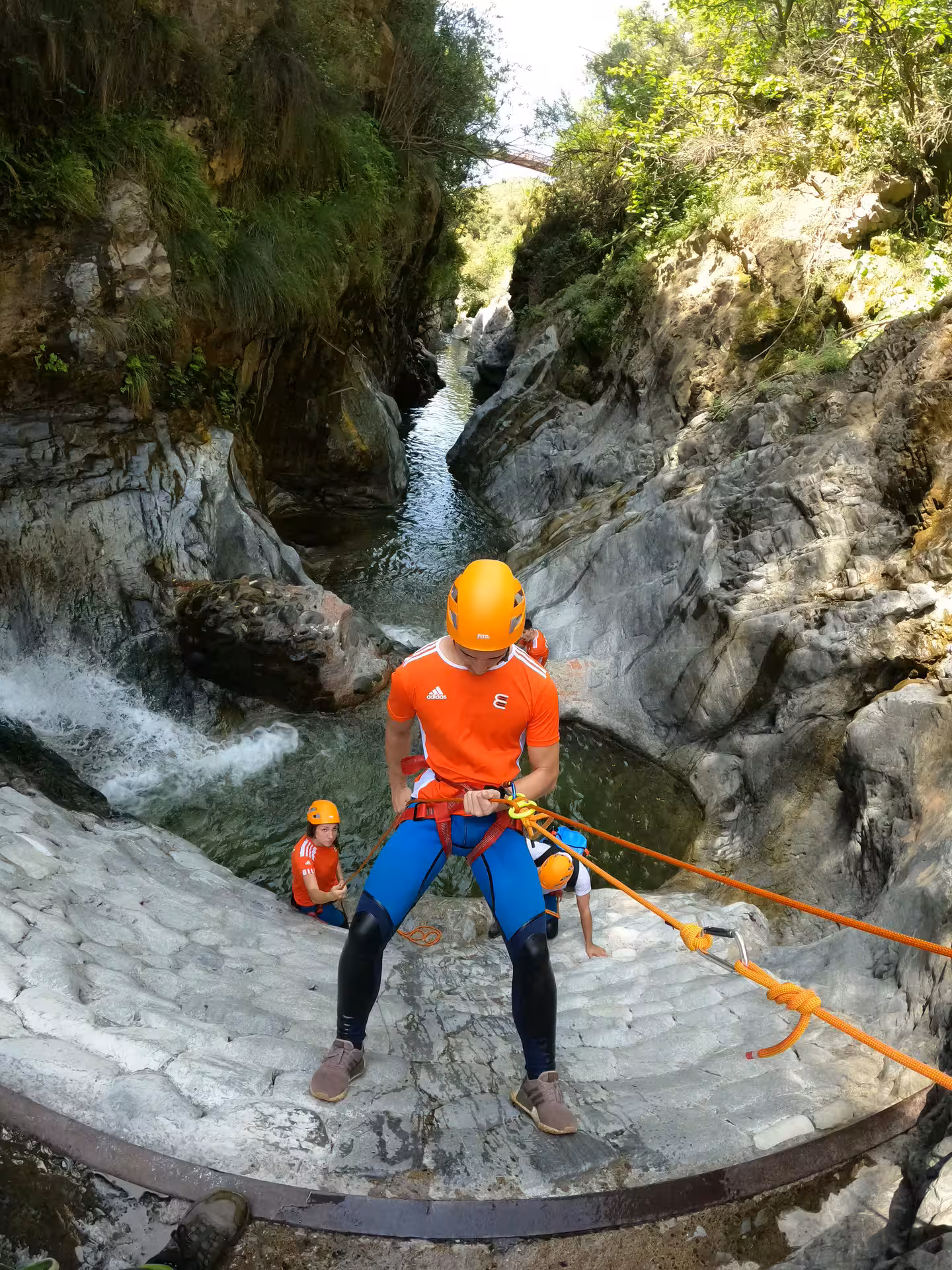 A helmeted adventurer rappels down a rocky waterfall during a guided canyoning tour in Guadalmina Canyon Estepona