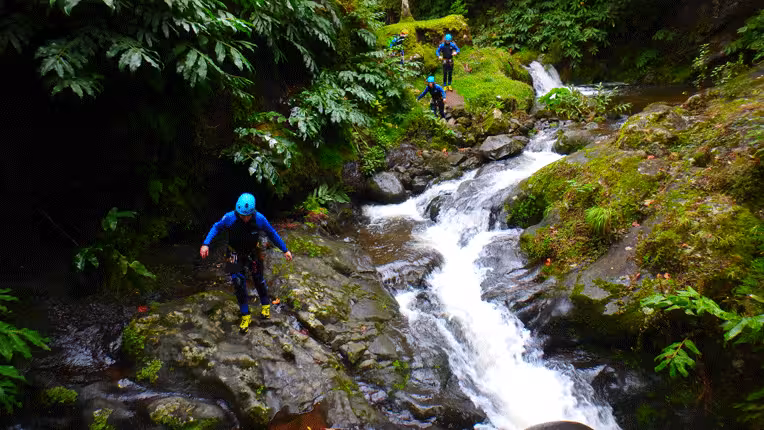 Guided canyoning in Ribeira dos Caldeirões, Azores, with wetsuits and helmets beside lush waterfalls
