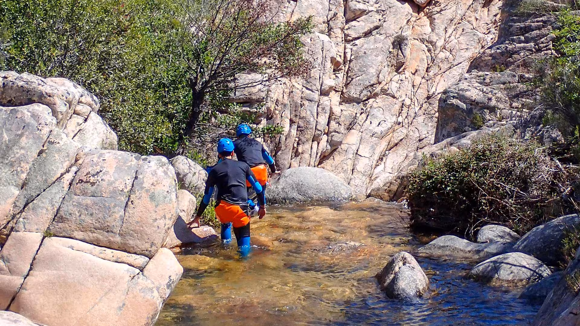 Canyoning enthusiasts navigating rocky terrain in Rio Pitrisconi, San Teodoro, amidst scenic natural landscapes.