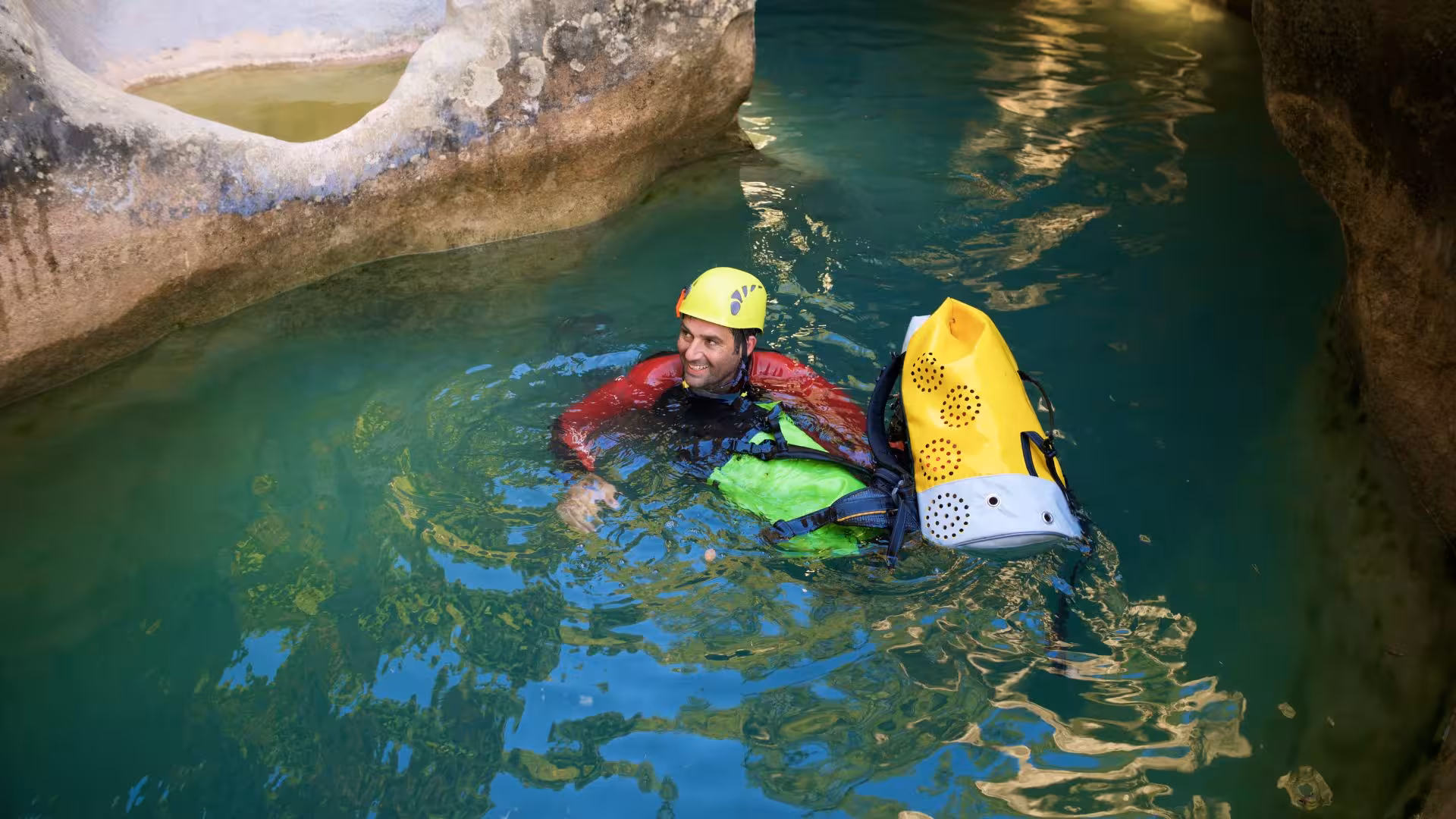 Canyoning enthusiast in vibrant wetsuit floating in turquoise waters of Rio Zairi, Villacidro, Sardinia.