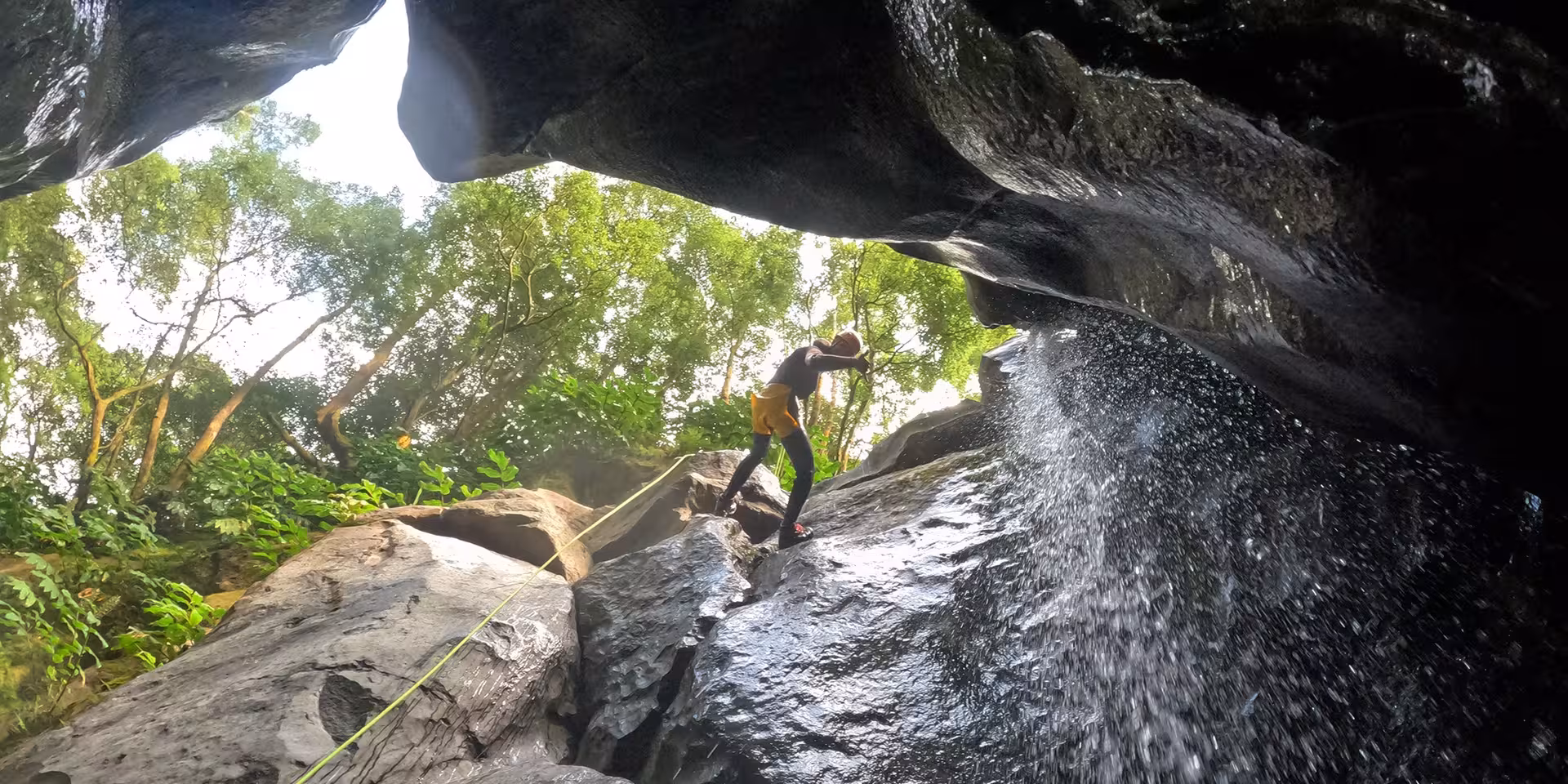 Rope-assisted canyoning on wet volcanic rocks near Salto do Cabrito waterfall, São Miguel Azores