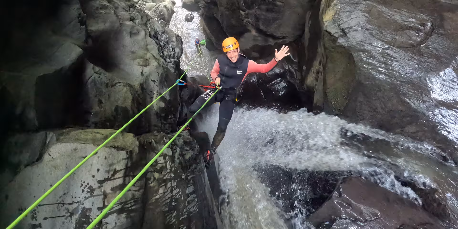Canyoning at Salto do Cabrito with a smiling climber rappelling beside a rushing waterfall canyon