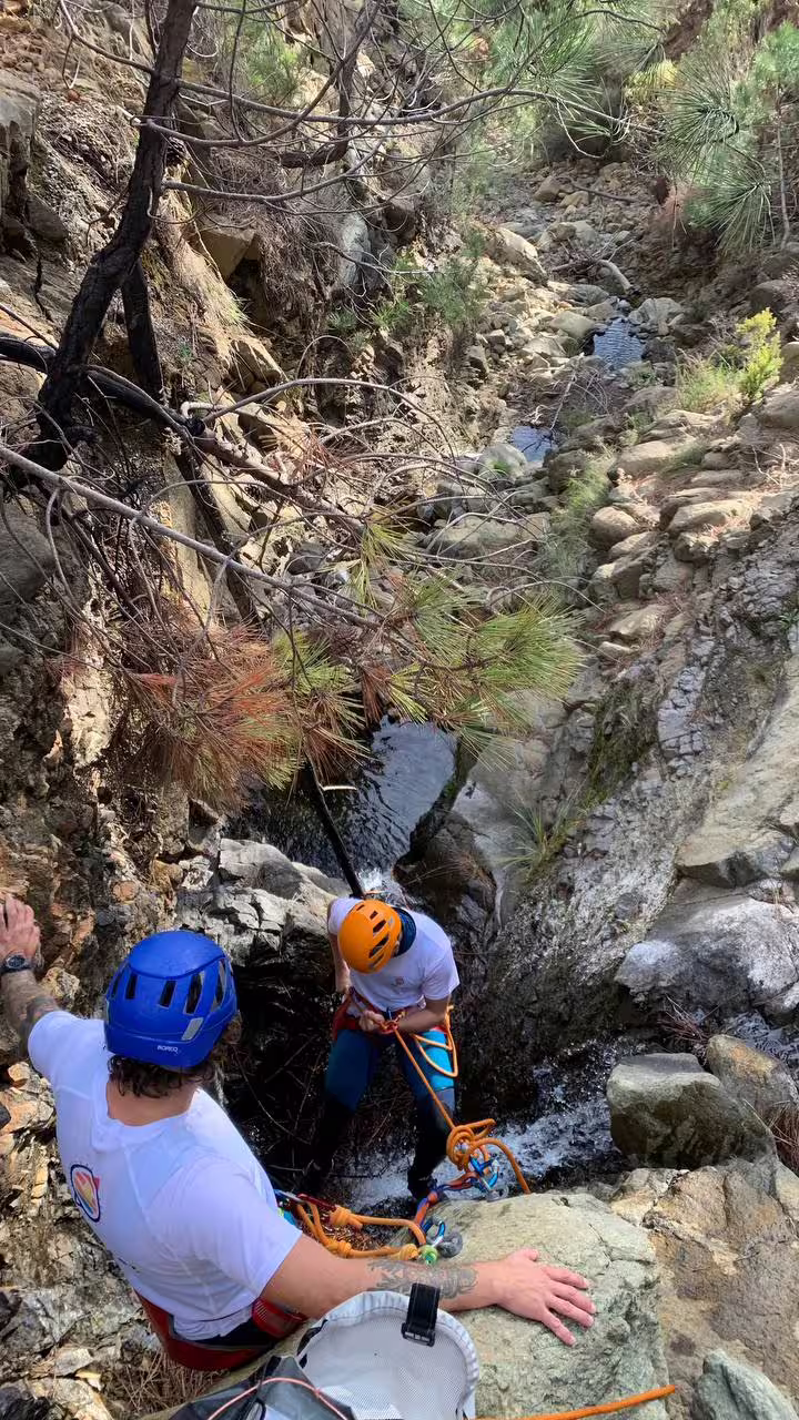 Two adventurers navigating a narrow canyon in Sierra Bermeja, Estepona, with ropes and helmets, showcasing thrilling nature exploration.