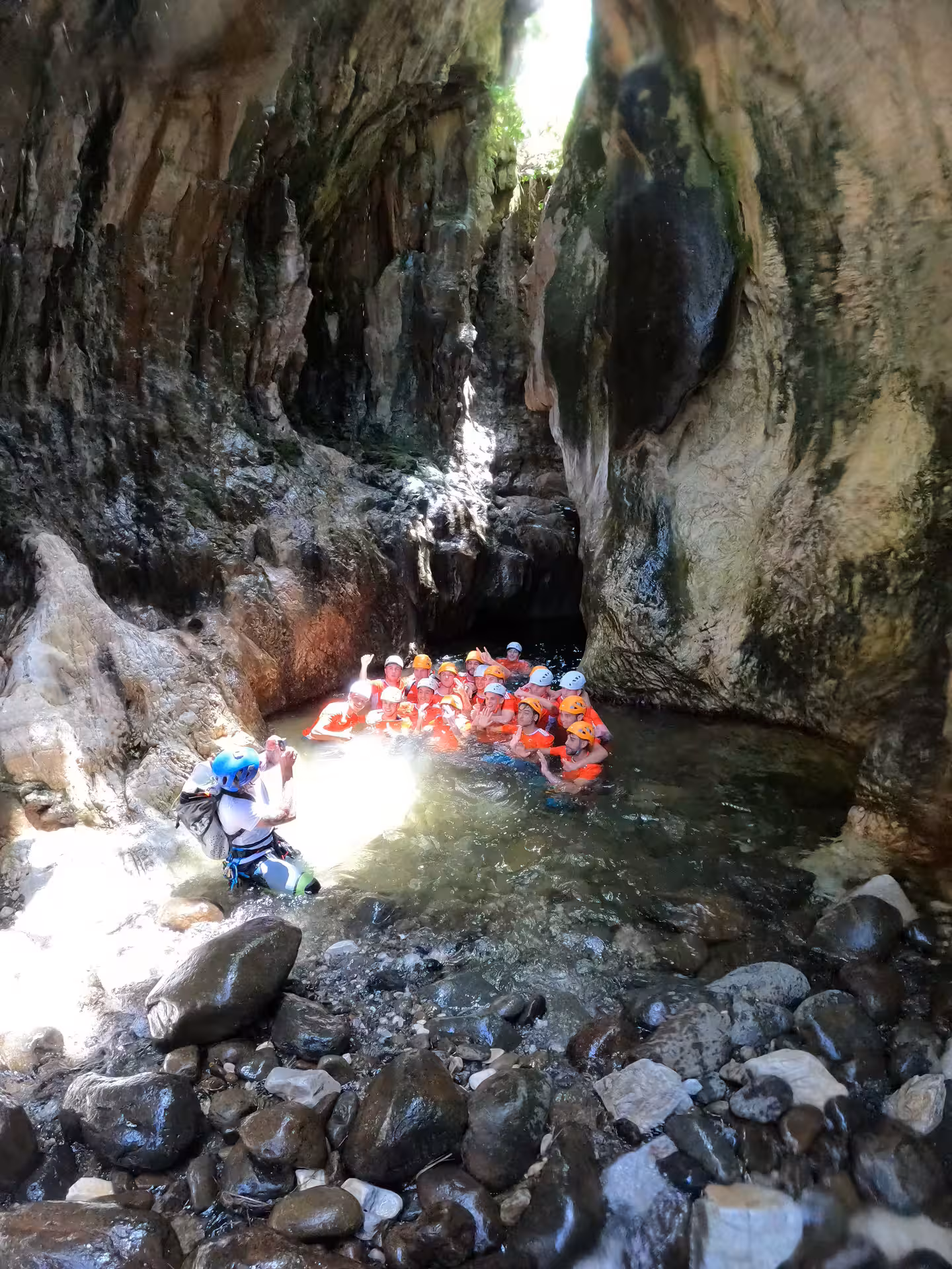 A group of canyoning adventurers wearing helmets swim through a narrow canyon gorge on a guided tour in Estepona