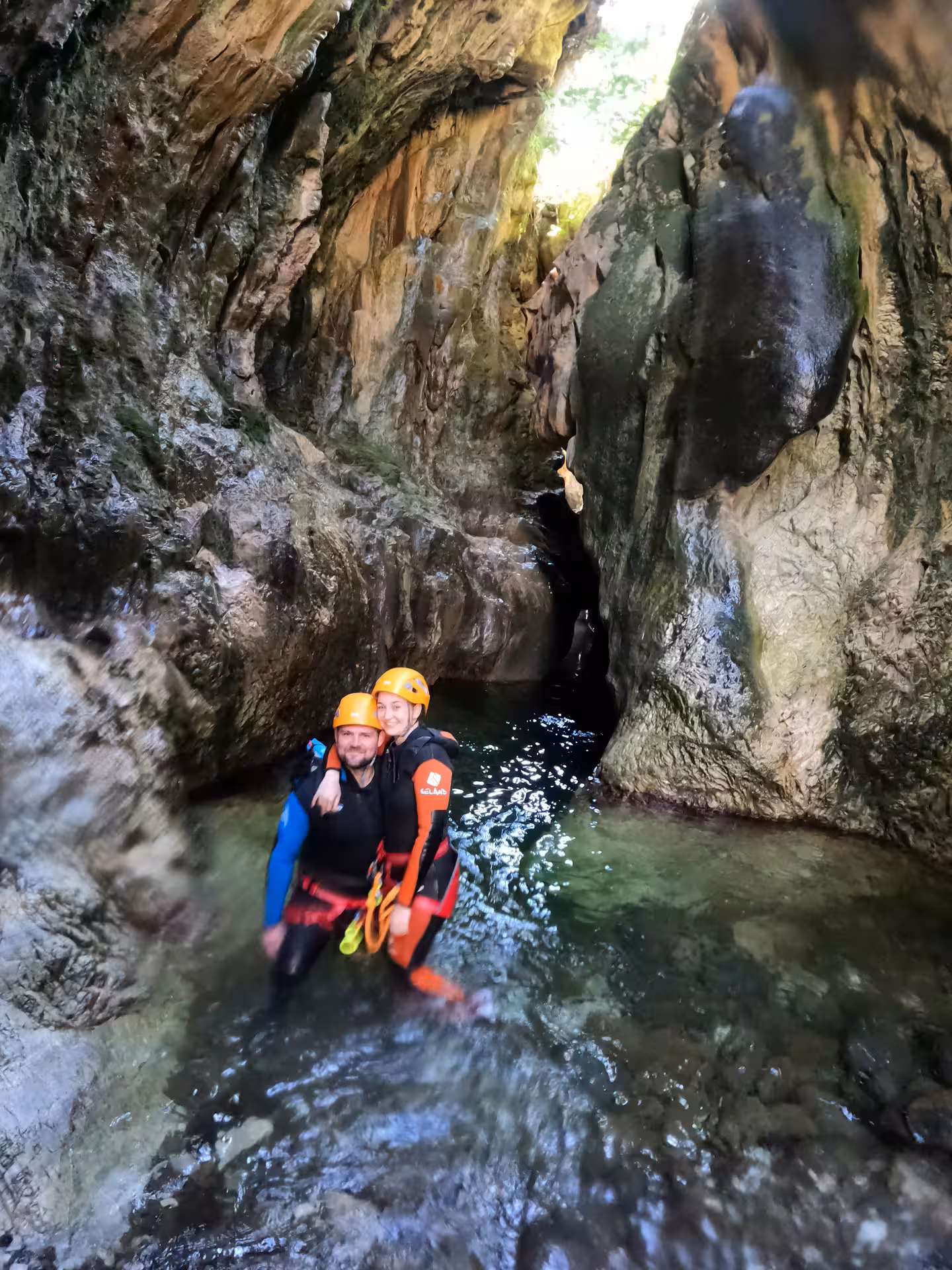 Couple in wetsuits and helmets wading through a narrow rocky gorge on a guided canyoning tour in Guadalmina Canyon Estepona
