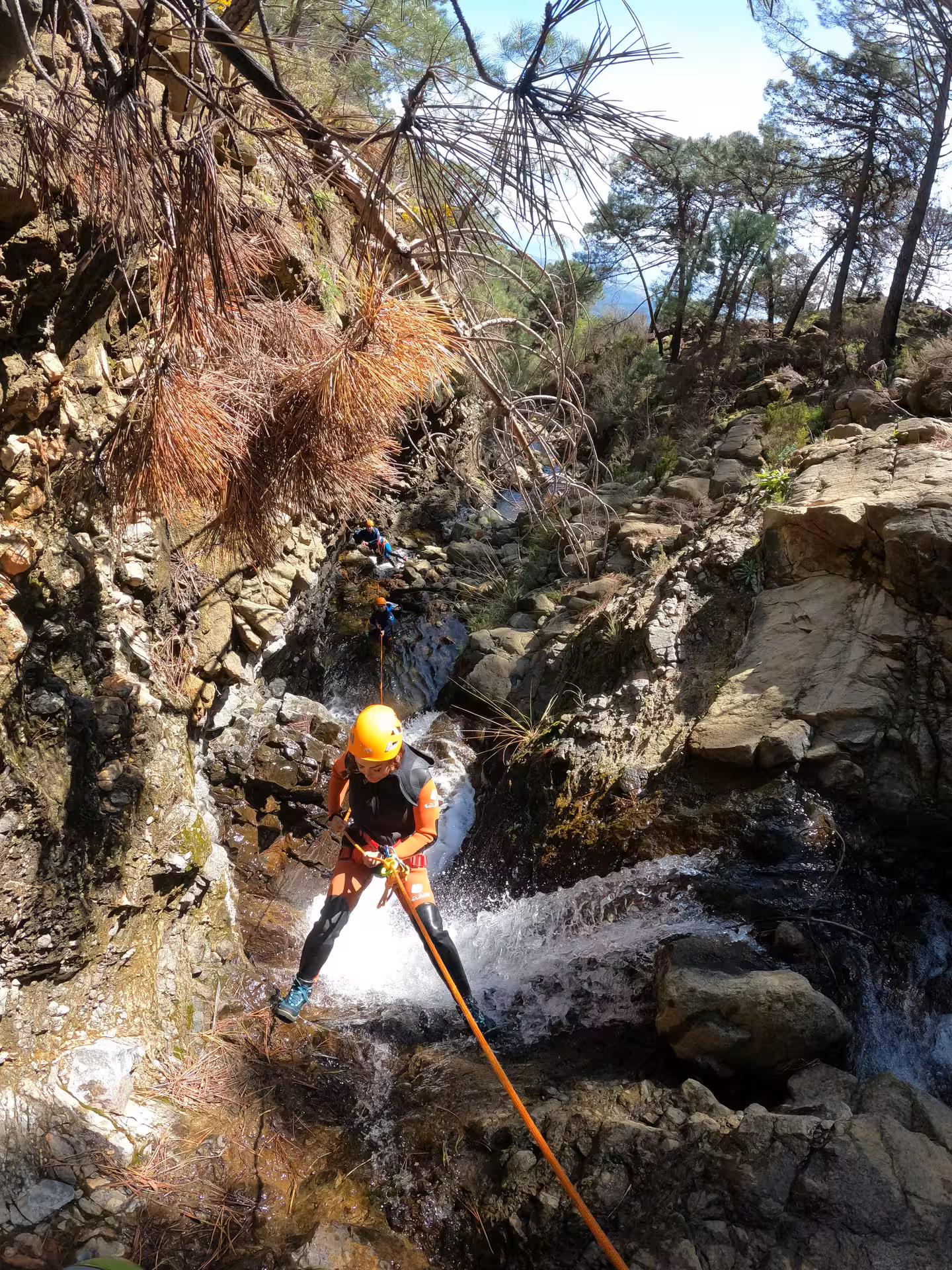 Adventure guide rappelling down a rocky waterfall during a guided canyoning tour in Sierra Bermeja, Estepona Spain.