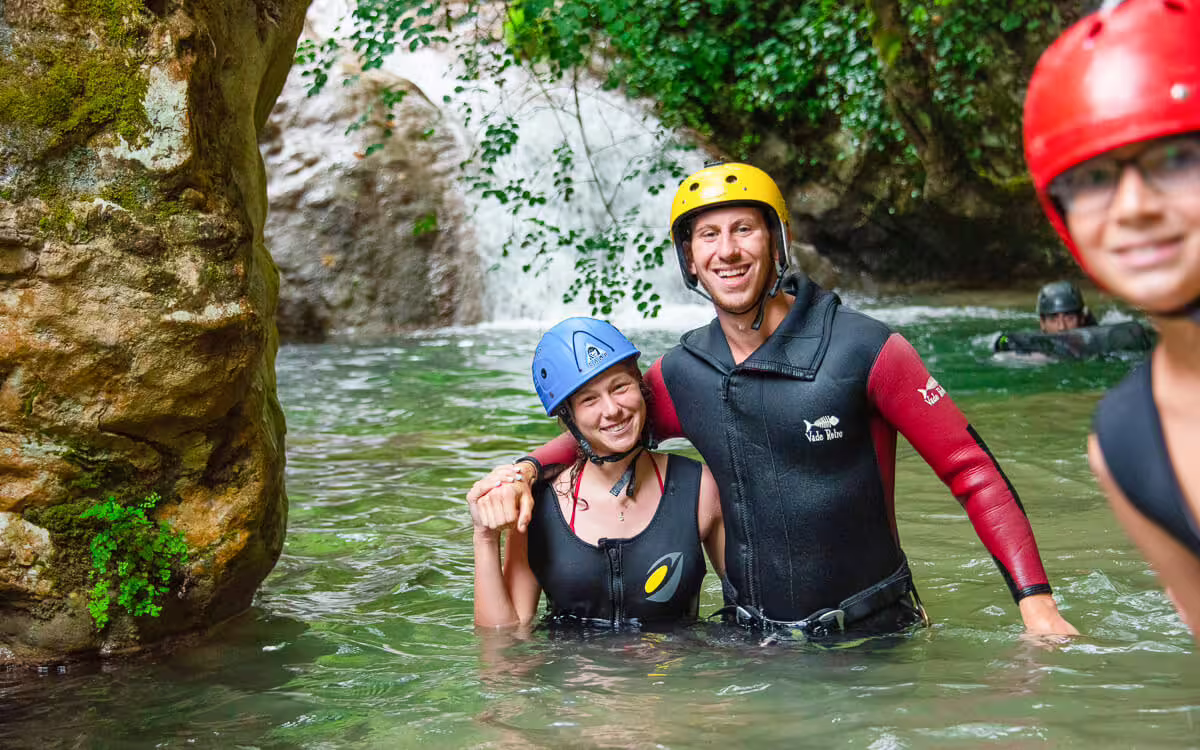 Canyoning group in wetsuits and helmets swimming in Polylimnio Waterfalls pool, Messinia Greece adventure tour