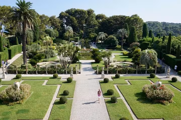Formal French garden with manicured hedges, palm trees, and a central pathway at Villa Ephrussi de Rothschild, Cap Ferrat