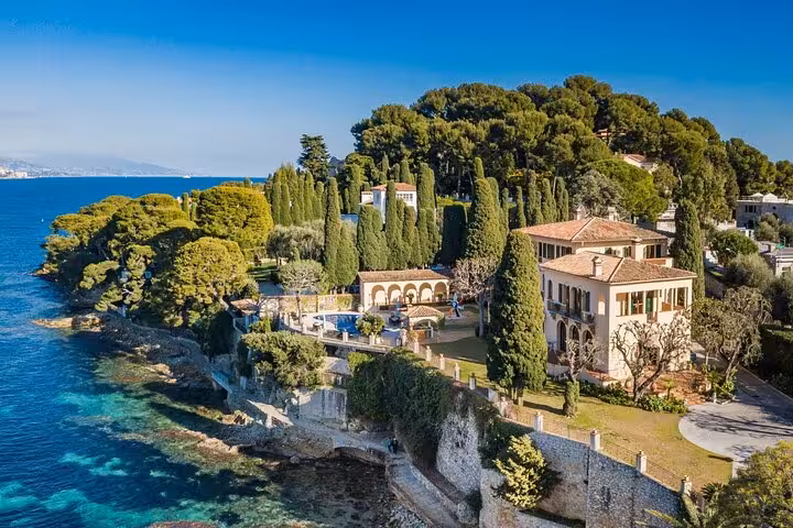Aerial view of luxury villa on rocky coastline at Cap Ferrat with turquoise Mediterranean Sea