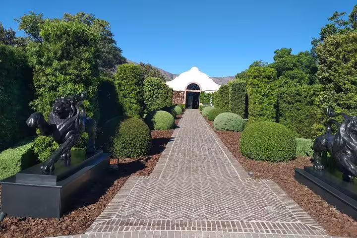 Sculpted garden path leading to elegant Cape Dutch building on Stellenbosch town tour.