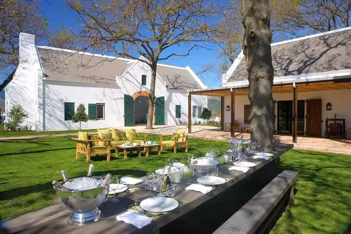 Charming Cape Dutch estate with outdoor dining setup for wine tasting tour near Cape Town winelands.