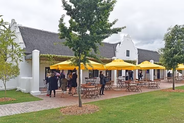 Tourists enjoying the sunny outdoor terrace at a Cape Dutch-style winery near Table Mountain.