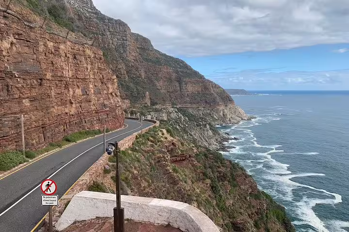 Scenic coastal road along the mountains at the Cape of Good Hope, offering breathtaking ocean views on a sunny day.