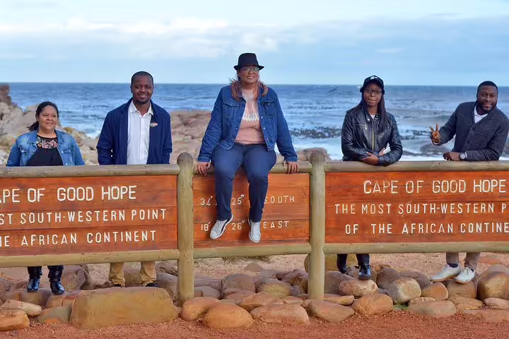 Group of tourists at the Cape of Good Hope sign, enjoying a sunny day on a private tour from Cape Town.