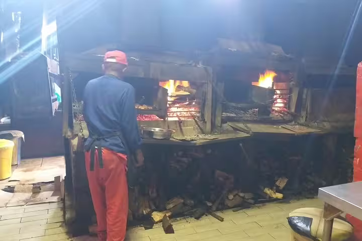Chef tending to traditional wood-fired ovens during Langa Township and Bo-Kaap cooking class tour.